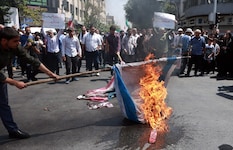Menschen im Iran verbrennen Flaggen von Israel und den USA.