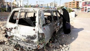 Eine verängstigte Frau begutachtet einen Krankenwagen des Iranischen Roten Halbmonds, der bei ...