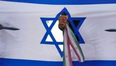 Eine iranische Faust, die eine israelische Flagge durchschlägt, bei einer Kundgebung in Teheran
