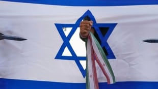 Eine iranische Faust, die eine israelische Flagge durchschlägt, bei einer Kundgebung in Teheran