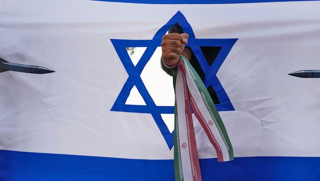 Eine iranische Faust, die eine israelische Flagge durchschlägt, bei einer Kundgebung in Teheran