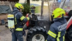 Feuerwehrleute schoben das Fahrzeug aus der Garage.
