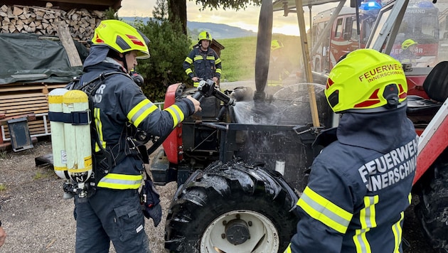 Feuerwehrleute schoben das Fahrzeug aus der Garage.