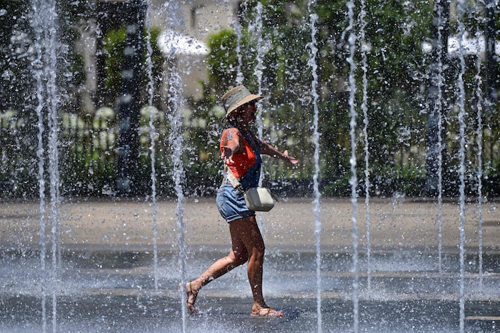 Eine Frau sucht in Wasserfontänen in Béziers, Südfrankreich, Erfrischung vor der anhaltenden ...