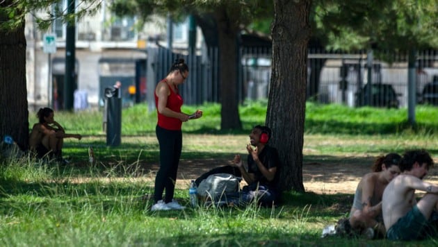 Menschen suchen in einem Park in Lissabon Zuflucht vor der Hitze.