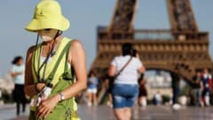 Eine Touristin in der französischen Hauptstadt schützt sich mit Hut und Gesichtsmaske vor den ...