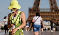Eine Touristin in der französischen Hauptstadt schützt sich mit Hut und Gesichtsmaske vor den ...