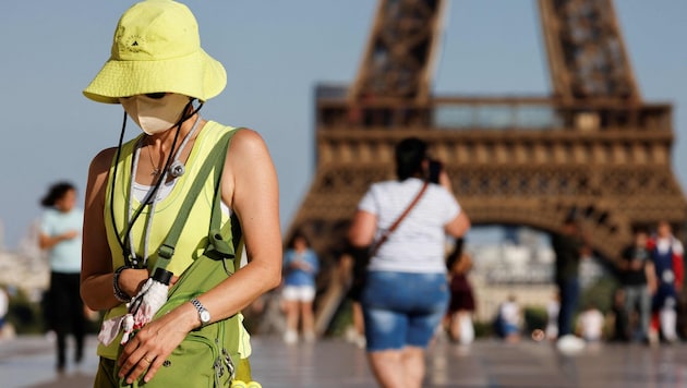 Eine Touristin in der französischen Hauptstadt schützt sich mit Hut und Gesichtsmaske vor den ...