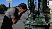 Ein Mann erfrischt sich bei einem öffentlichen Brunnen in Paris.