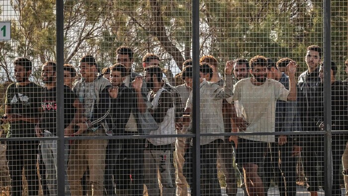 Menschen stehen hinter einem Zaun, nachdem sie in Lavrio von Bord gegangen sind.