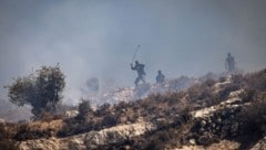 Maskierte israelische Siedler schleudern Steine auf die Häuser von dort wohnenden ...