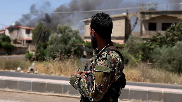 Ein syrischer Soldat vor brennenden Häusern in Suweida