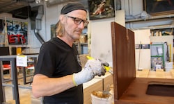 Im Malersaal werden Oberflächen veredelt: Wolfgang Kschwendt beizt ein Regal ab.