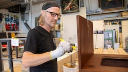 Im Malersaal werden Oberflächen veredelt: Wolfgang Kschwendt beizt ein Regal ab.