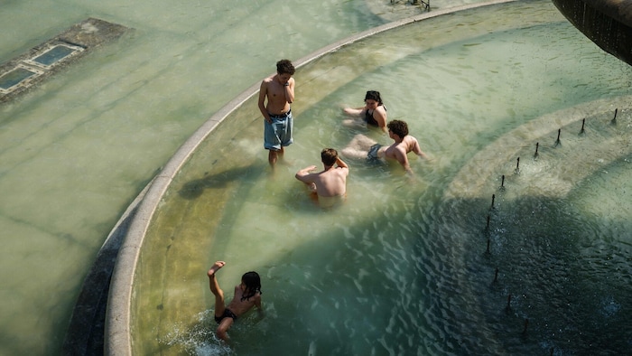 Kind und Jugendliche beim Baden in einem Brunnen in Paris