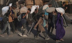 Palästinenser tragen Säcke mit Mehl, die aus einem humanitären Hilfskonvoi entladen wurden,