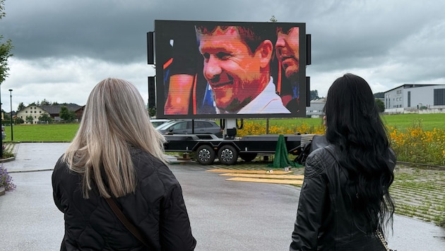 Auf einer Videoleinwand vor der Trauerhalle werden Szenen aus Baumgartners Leben gezeigt.