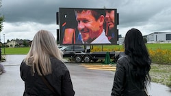 Auf einer Videoleinwand vor der Trauerhalle werden Szenen aus Baumgartners Leben gezeigt.