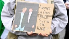 Eine Demonstrantin hält ein Plakat, auf dem Epstein und Trump abgebildet sind.