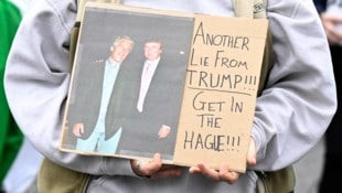 Eine Demonstrantin hält ein Plakat, auf dem Epstein und Trump abgebildet sind.