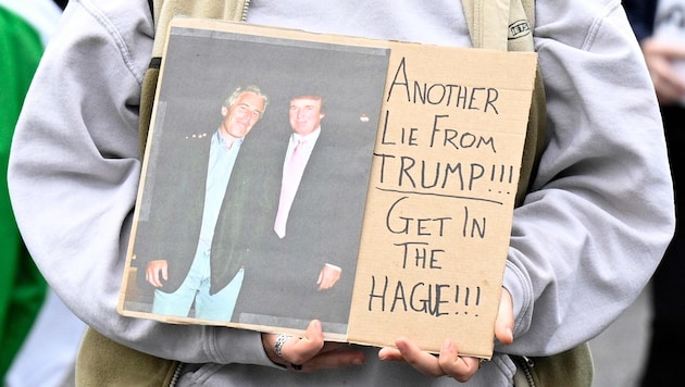 Eine Demonstrantin hält ein Plakat, auf dem Epstein und Trump abgebildet sind.