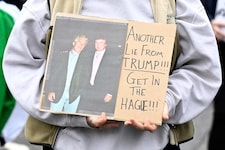 Eine Demonstrantin hält ein Plakat, auf dem Epstein und Trump abgebildet sind.