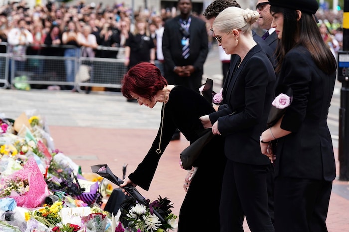In schwarzes Papier gewickelt, legt Sharon Osbourne eine lilafarbene Blume nieder.