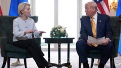 EU-Chefin Ursula von der Leyen und US-Präsident Donald Trump. Trump hält einen Zettel in der ...