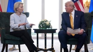 EU-Chefin Ursula von der Leyen und US-Präsident Donald Trump. Trump hält einen Zettel in der ...