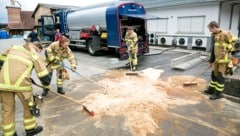 Die Einsatzkräfte der Feuerwehr beim Zusammenkehren des Sägemehls.