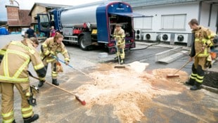 Die Einsatzkräfte der Feuerwehr beim Zusammenkehren des Sägemehls.