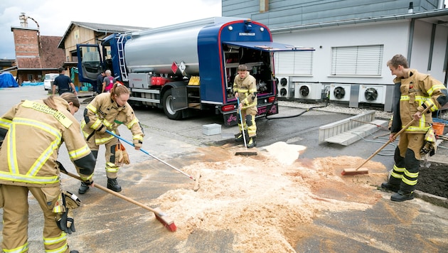 Die Einsatzkräfte der Feuerwehr beim Zusammenkehren des Sägemehls.