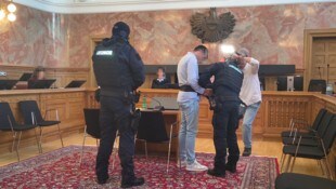 Bewaffnete und maskierte Justizwachebeamten passten im Verhandlungssaal auf den ...