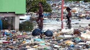 Kinder waten auf Tuvalu durch Wassermassen und Müll (Archivbild).
