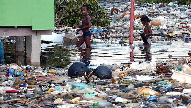 Kinder waten auf Tuvalu durch Wassermassen und Müll (Archivbild).