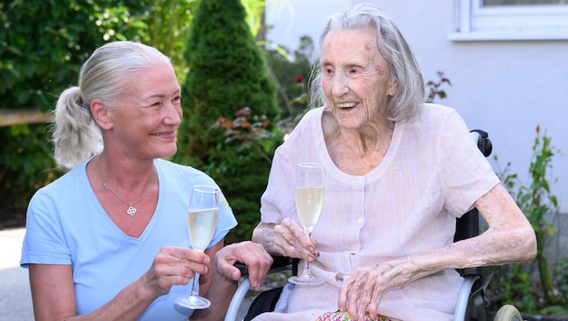 Pflegerin Doreen Leitinger stößt mit der 104-jährigen Irmgard Perfahl an.