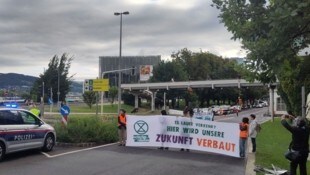 Der Protest sorgt bereits für Chaos im Frühverkehr – an der Brücke haben sich zwei Aktivisten ...