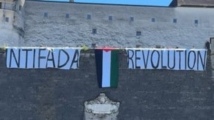 Protestplakate und die Flagge Palästinas auf der Festung.