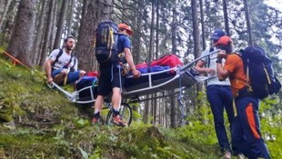 Bergretter tragen eine verletzte Wanderin über den Steinalmweg ins Tal.