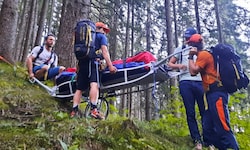 Bergretter tragen eine verletzte Wanderin über den Steinalmweg ins Tal.