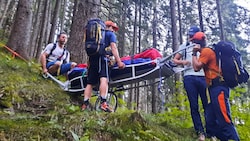 Bergretter tragen eine verletzte Wanderin über den Steinalmweg ins Tal.