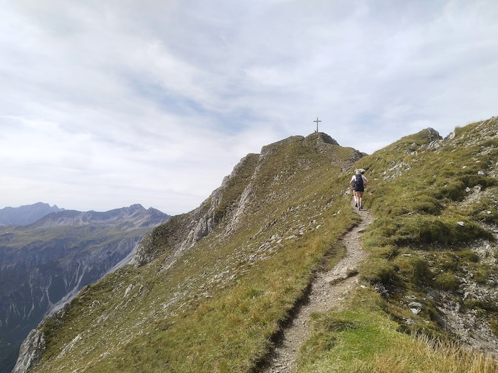 Die letzten Meter zum Hauptgipfel führen durch eine abschüssige Wiesenflanke.