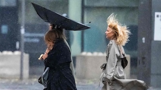 Menschen kämpfen gegen Wind und Regen, während sie die Straße entlanggehen, als der Sturm am 5. ...