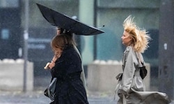 Menschen kämpfen gegen Wind und Regen, während sie die Straße entlanggehen, als der Sturm am 5. ...