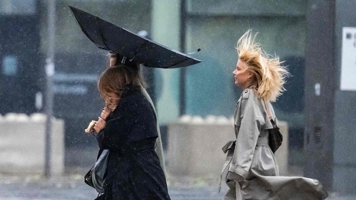 Menschen kämpfen gegen Wind und Regen, während sie die Straße entlanggehen, als der Sturm am 5. ...