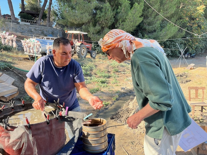 Ein einheimischer Helfer zeigt stolz seinen Pflanzenfund im Schlamm.