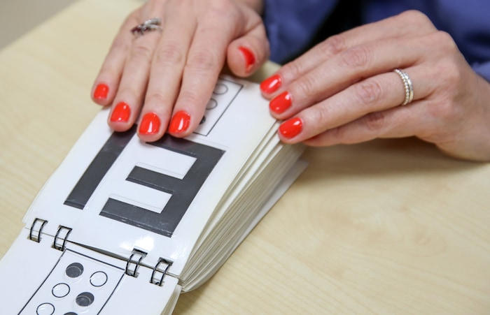 Heidi Geyer ertastet die Buchstaben. Darunter stehen sie in Brailleschrift.