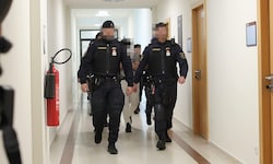 Drei Angeklagte werden schwer bewacht aus der U-Haft vorgeführt.