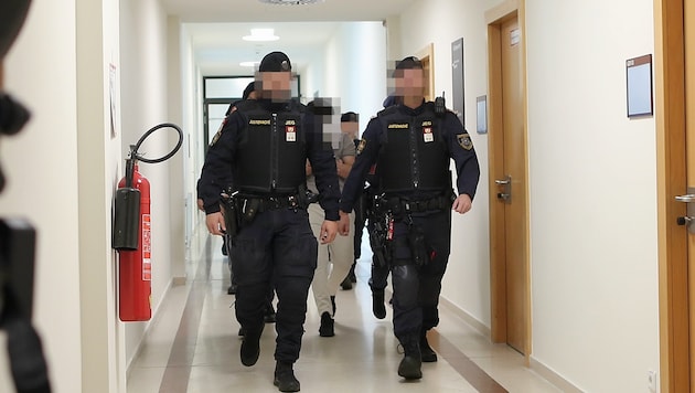 Drei Angeklagte werden schwer bewacht aus der U-Haft vorgeführt.