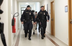 Drei Angeklagte werden schwer bewacht aus der U-Haft vorgeführt.